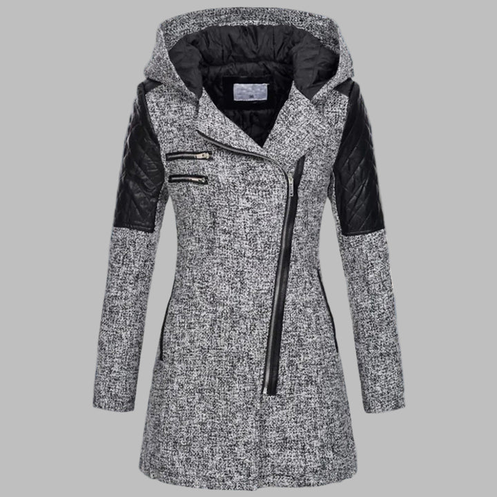 Grijze dames winterjas met capuchon, asymmetrische ritssluiting en zwarte leren accenten, ideaal voor koude weersomstandigheden en modieuze winterstijl.